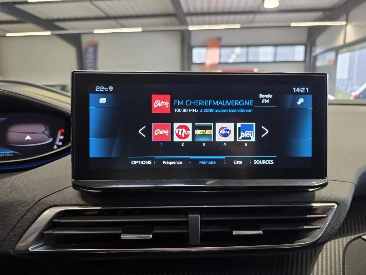 Écran tactile central du Peugeot 3008 2022 affichant la radio FM dans un intérieur avec décors carbone.
