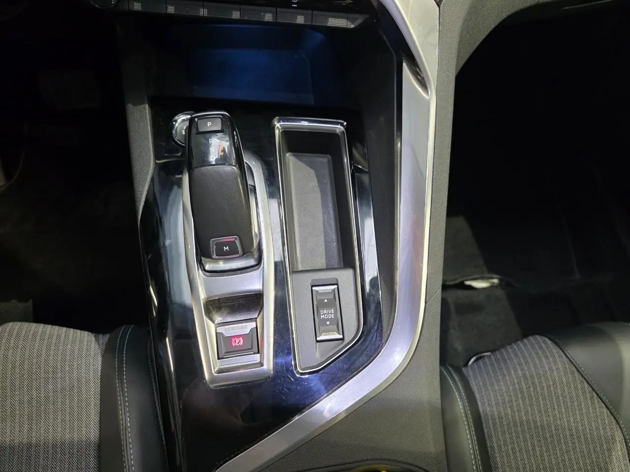 Gros plan sur la console centrale noire brillante du Peugeot 3008 avec levier de vitesse automatique et bouton Drive Mode.