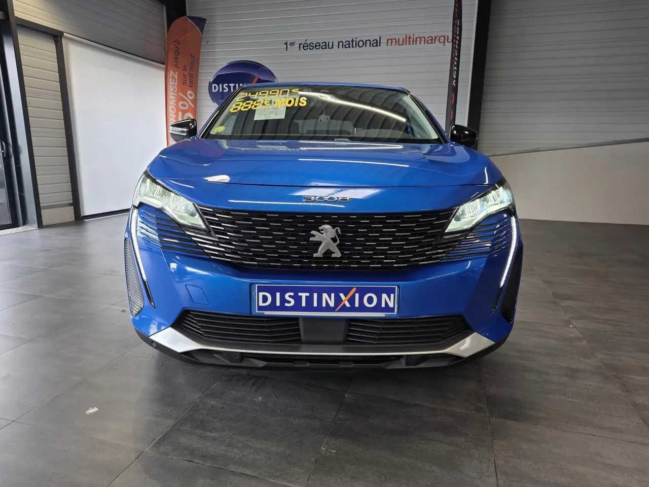 Vue avant d'un Peugeot 3008 bleu Iron avec calandre noire et logo lion chromé, en showroom intérieur.