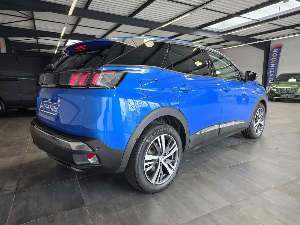 Peugeot 3008 bleu Iron vue 3/4 arrière droit en intérieur, avec jantes alliage bi-ton et vitres surteintées.