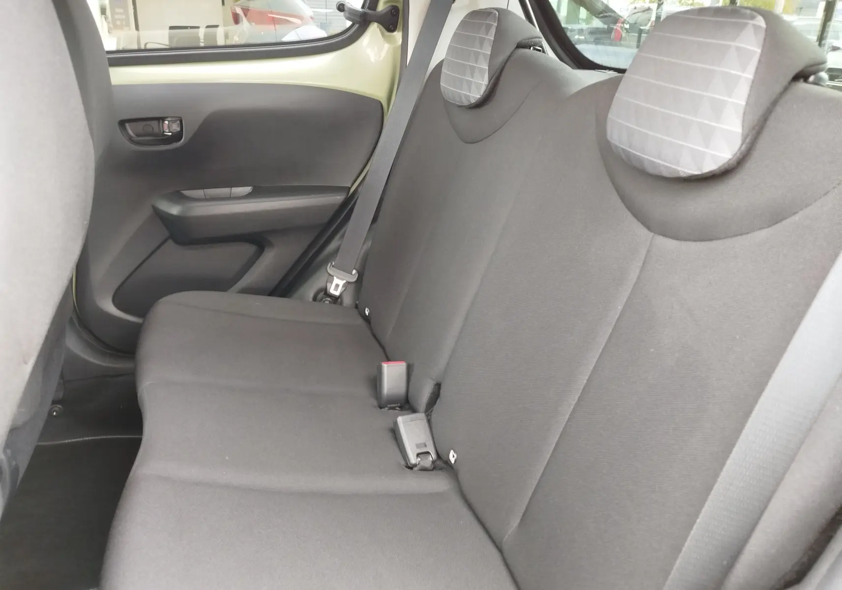 Vue intérieure côté droit des sièges arrière noirs avec appuie-têtes gris à motifs dans une Peugeot 108 Smooth Green 2021.