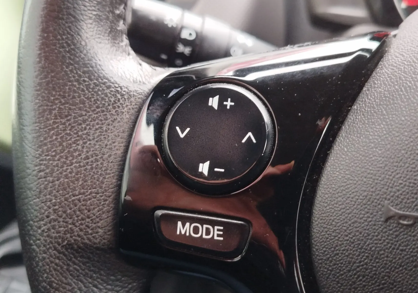 Gros plan sur les commandes audio au volant noir d'une Peugeot 108 2021, boutons volume et mode visibles.