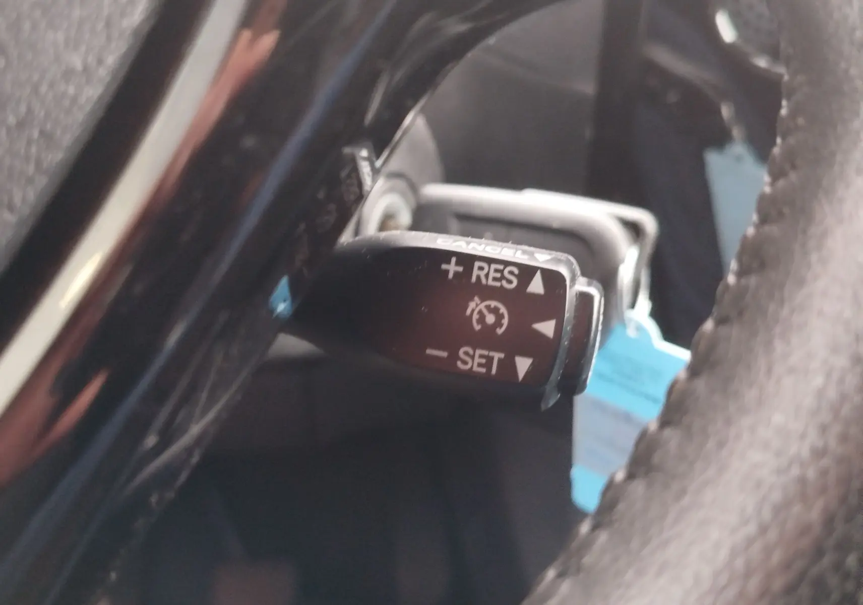 Gros plan sur la commande de régulateur de vitesse derrière le volant d’une Peugeot 108 2021, intérieur noir.
