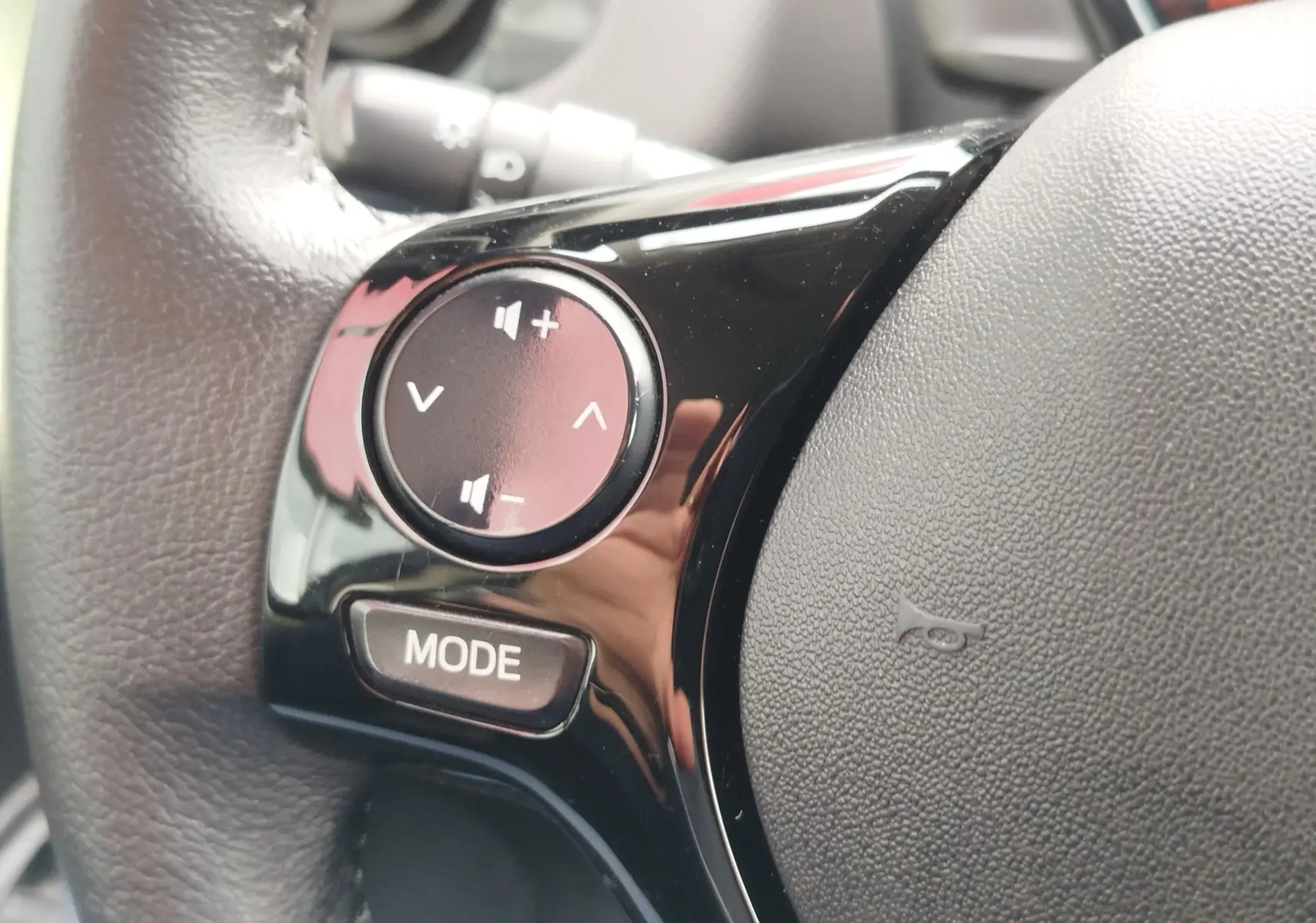 Gros plan sur les commandes audio noires intégrées au volant en cuir gris d'une Peugeot 108 2021.