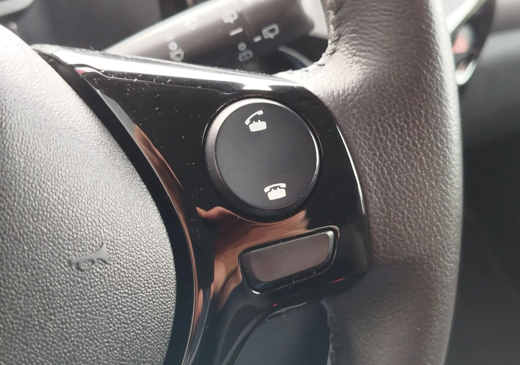 Gros plan sur les commandes d’appel téléphonique sur le volant en cuir noir du Peugeot 108 2021.