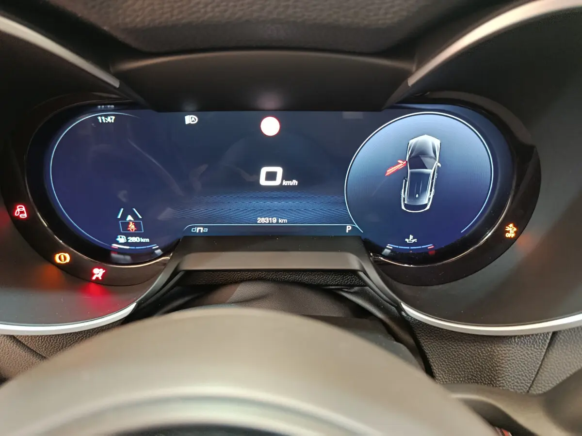 Vue rapprochée du combiné d'instruments numérique de l'Alfa Romeo Stelvio 2.2 TD 160 AT8 Sprint affichant la vitesse à 0 km/h et alertes actives.