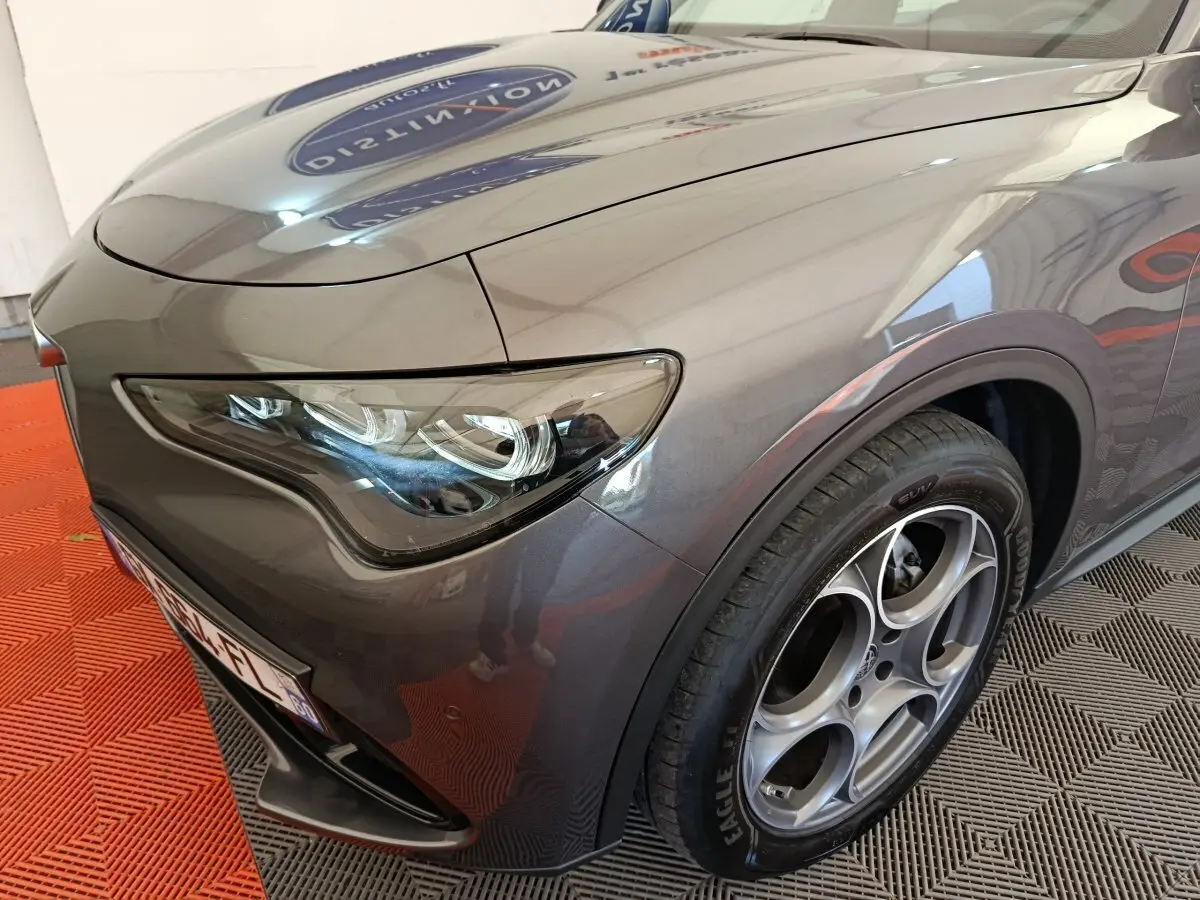 Gros plan sur l'avant droit gris foncé de l'Alfa Romeo Stelvio 2.2 TD 160 AT8 Sprint avec phares LED et jante distinctive.