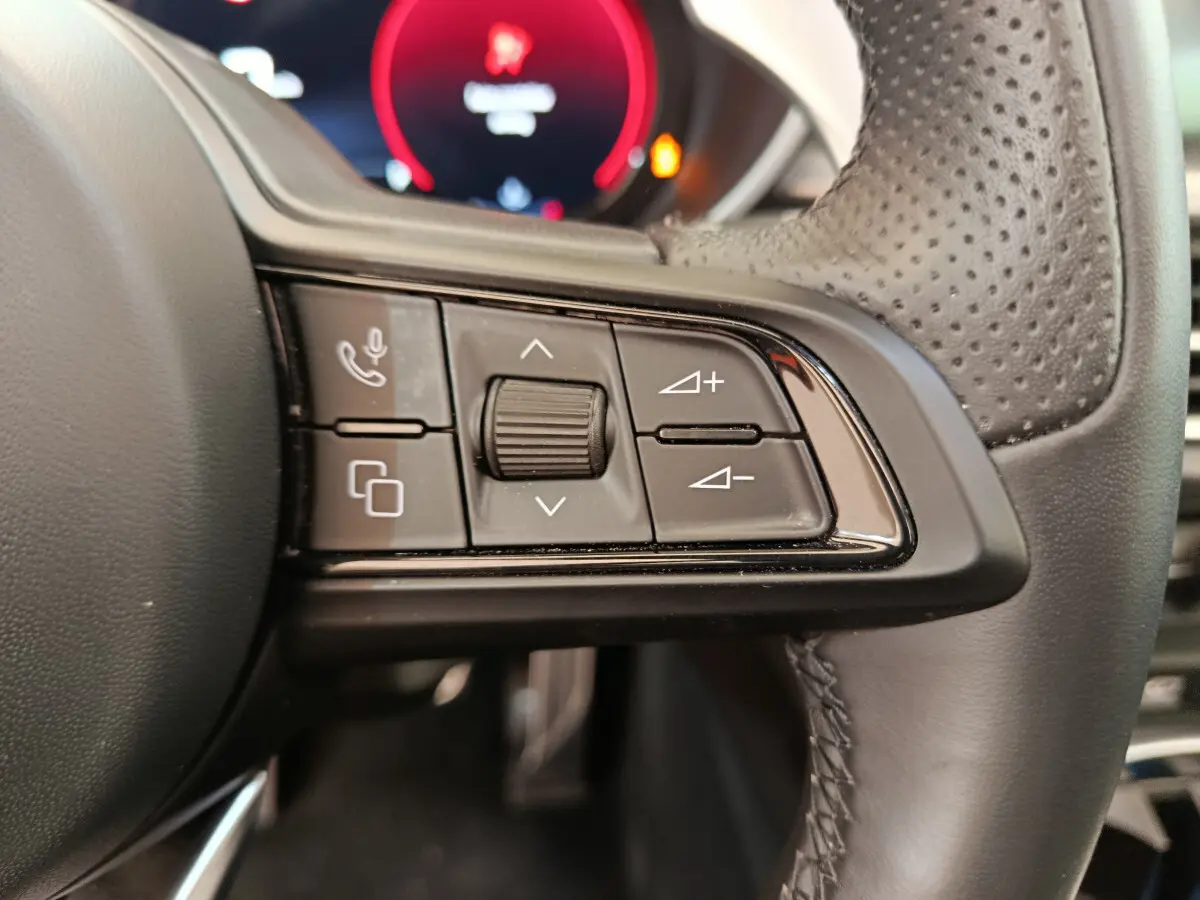 Gros plan sur les commandes multifonctions à droite du volant en cuir perforé de l'Alfa Romeo Stelvio gris foncé 2024.