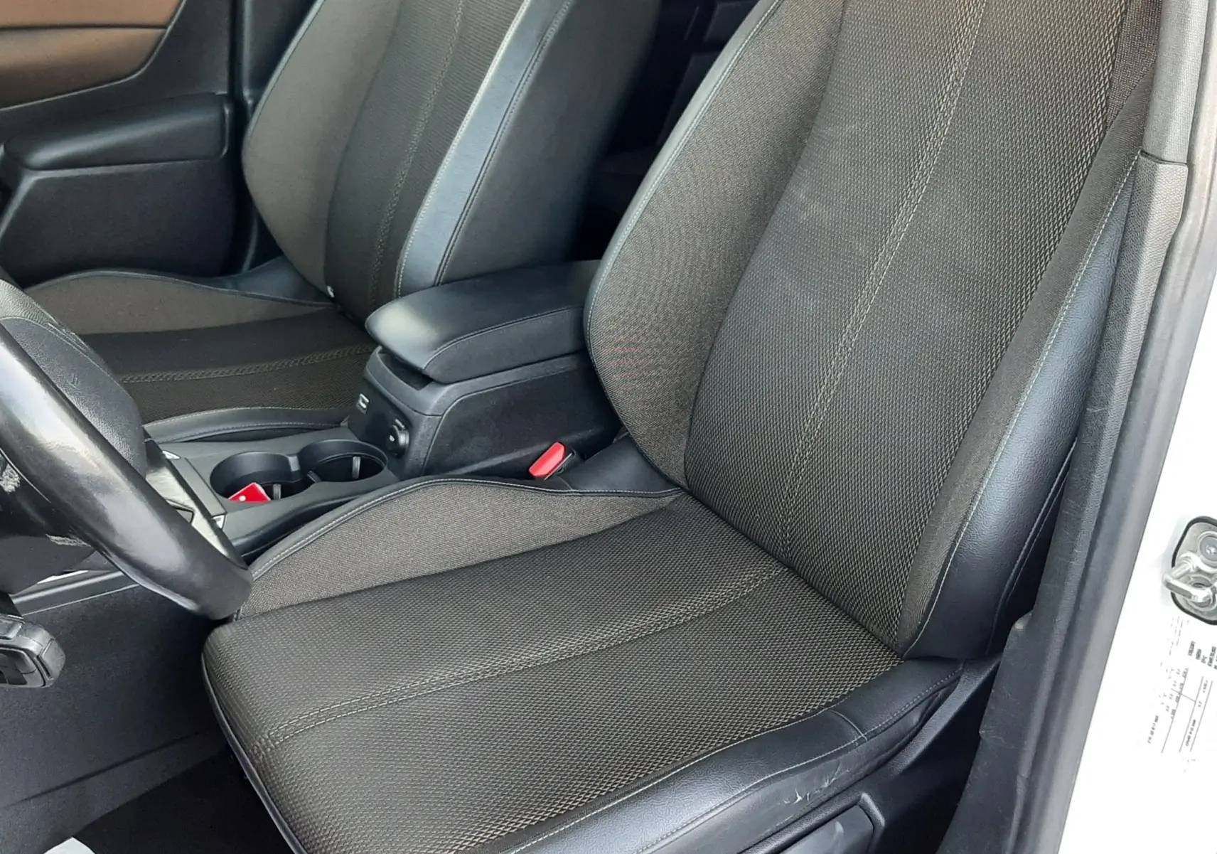 Vue intérieure côté conducteur du DS3 Crossback 2019, sièges tissu noir avec surpiqûres et accoudoir central.