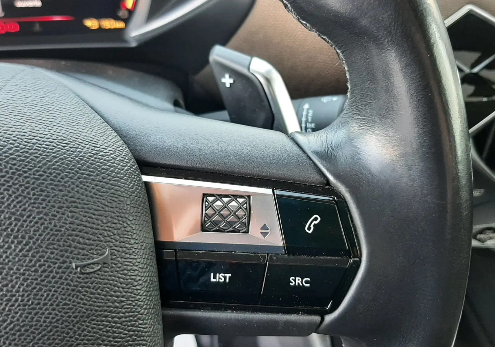 Gros plan sur la partie gauche du volant en cuir noir du DS3 Crossback 2019, avec commandes audio et téléphone intégrées.