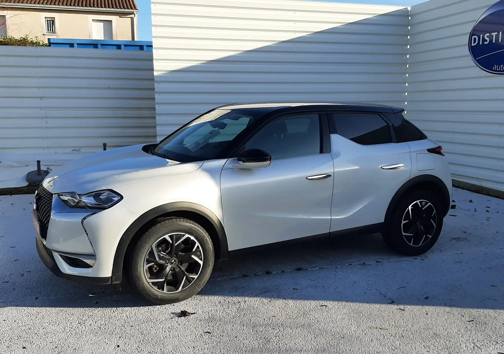 Vue 3/4 avant droit d'un DS3 Crossback blanc perle avec toit noir et jantes noires en alliage.