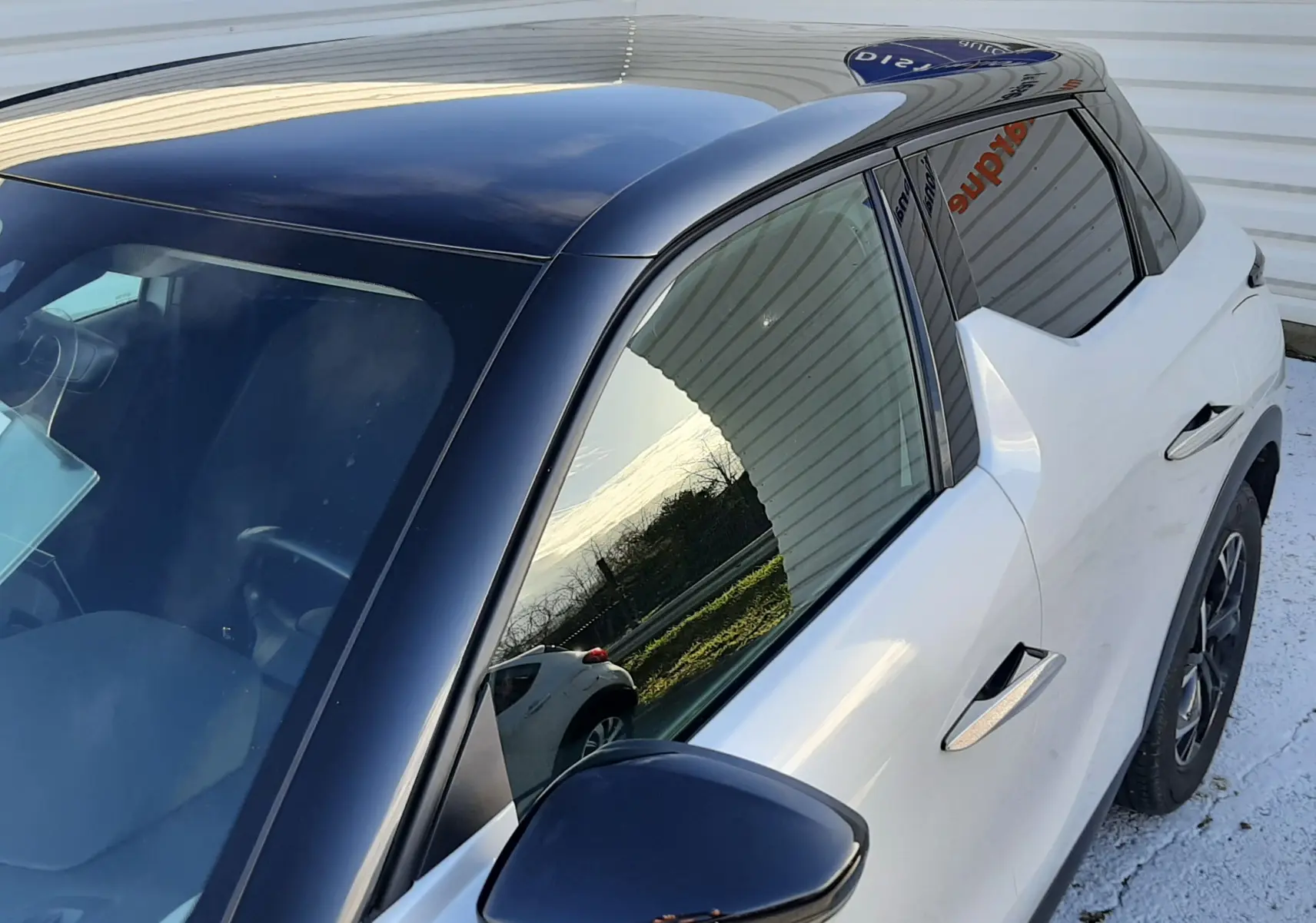 Vue rapprochée côté gauche d'une DS3 Crossback blanc perle avec toit noir brillant et rétroviseur assorti.