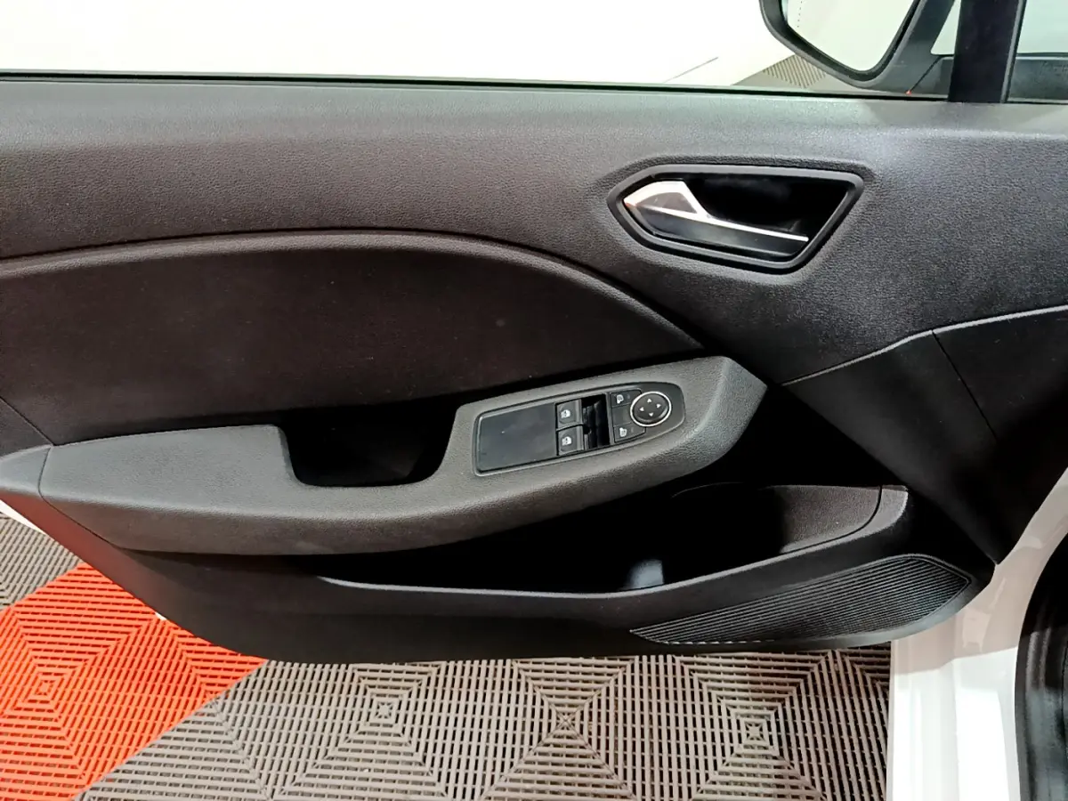Intérieur côté gauche de la porte avant d'une Renault Clio Business blanche, avec commandes électriques des vitres et poignée noire.