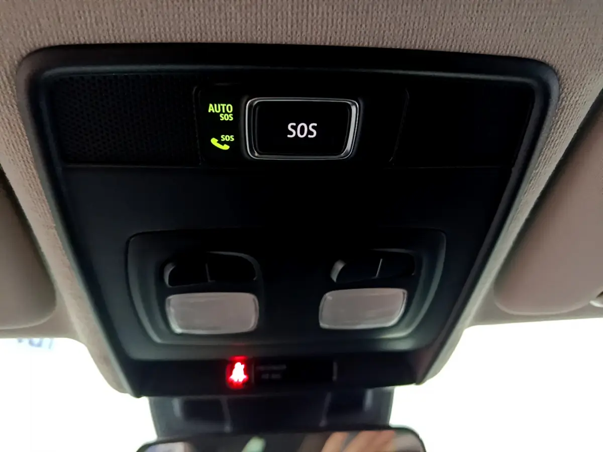 Gros plan sur le plafonnier intérieur noir avec bouton SOS éclairé en vert et lampe rouge dans une Renault Clio blanche 2021.