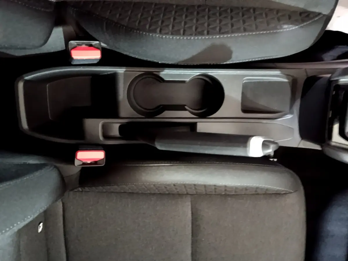 Vue plongeante sur la console centrale noire de la Renault Clio Business TCe 90 avec frein à main manuel et sièges tissu.