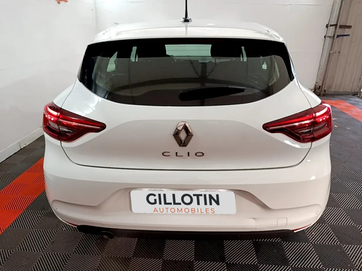 Vue arrière d'une Renault Clio Business blanche garée en intérieur avec feux arrière LED allumés.