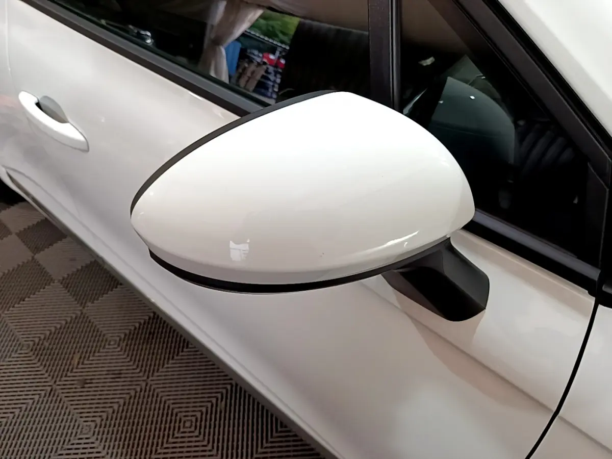 Rétroviseur droit blanc de la Renault Clio Business TCe 90 2021, avec portière et poignée assortis visibles en arrière-plan.