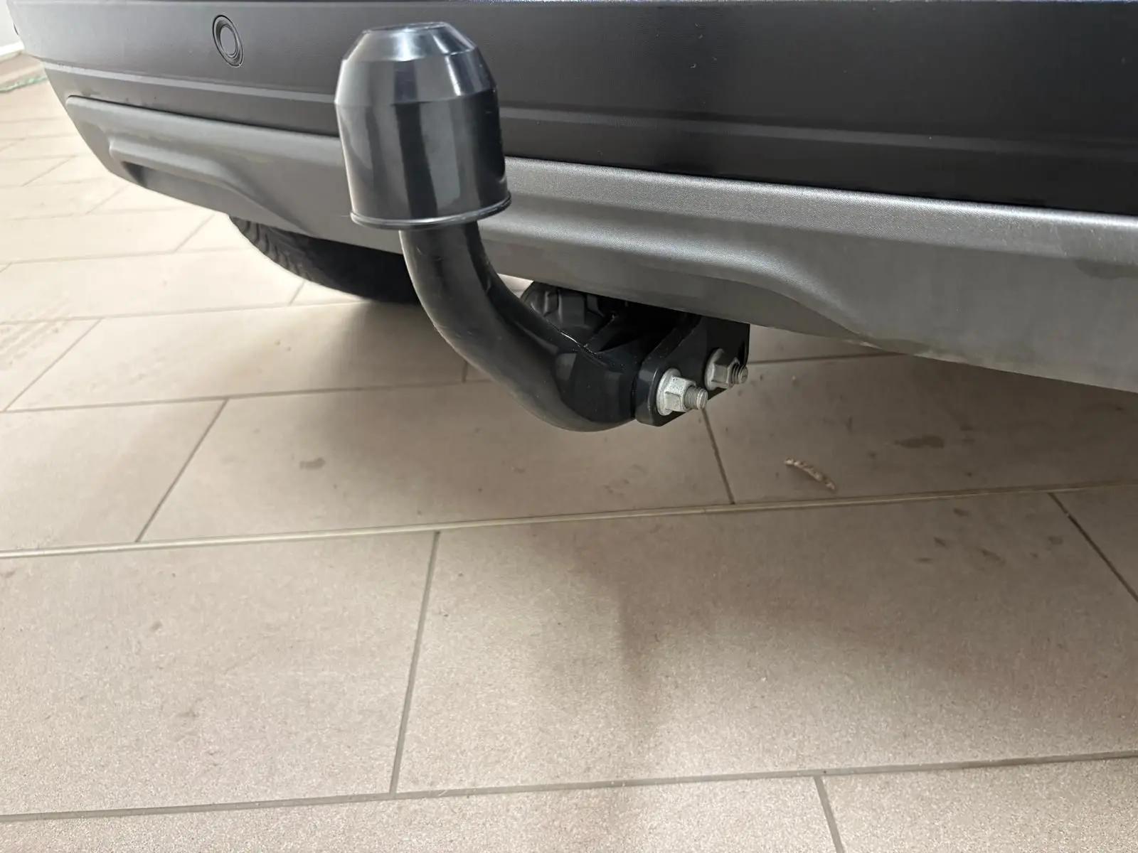 Gros plan sur l'attelage arrière noir du Dacia Sandero Stepway 2023 en Vert Cèdre, vue centrée sous le pare-chocs.