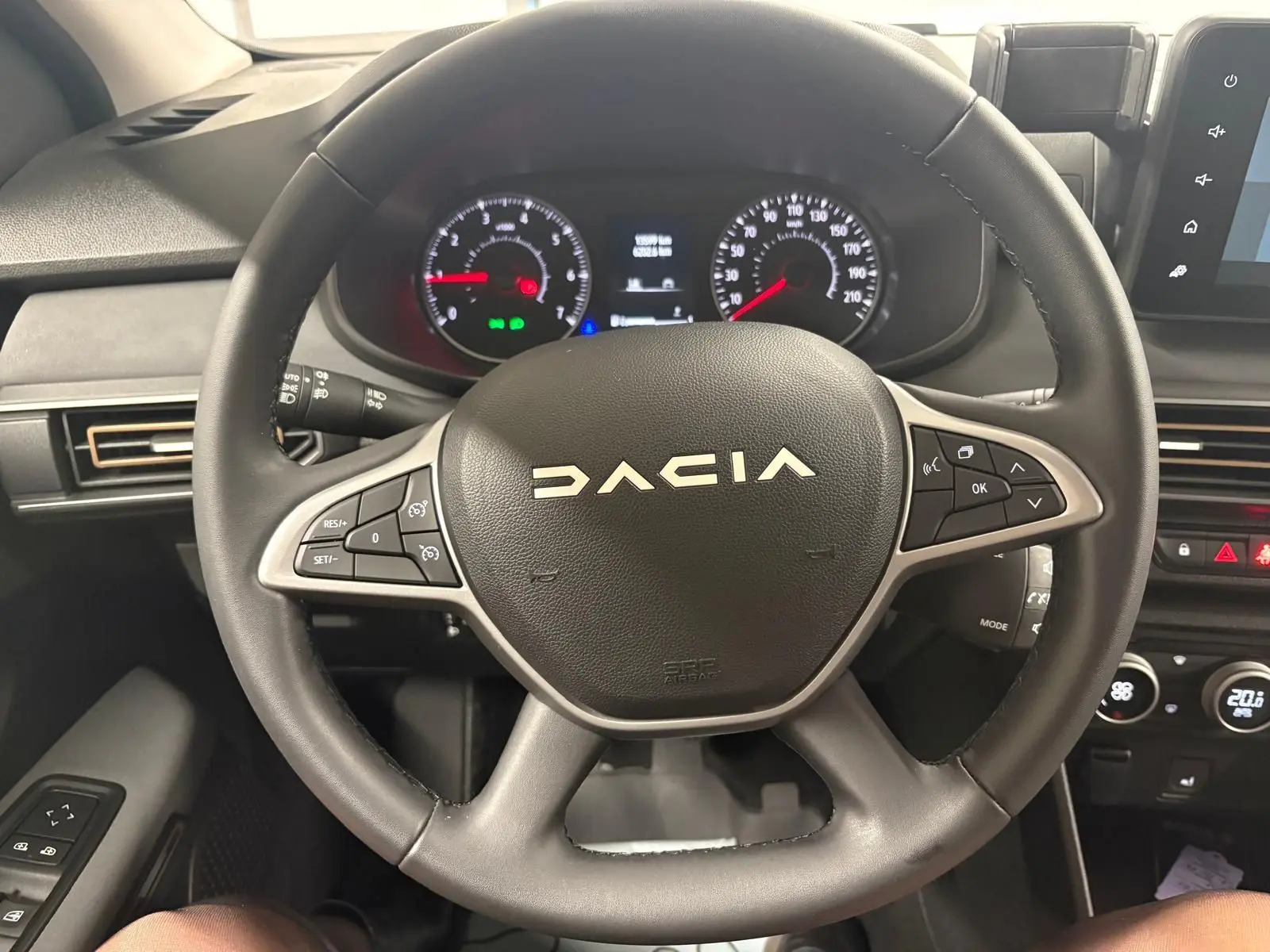 Vue rapprochée du volant noir de la Dacia Sandero Stepway 2023 avec tableau de bord et commandes au volant visibles.