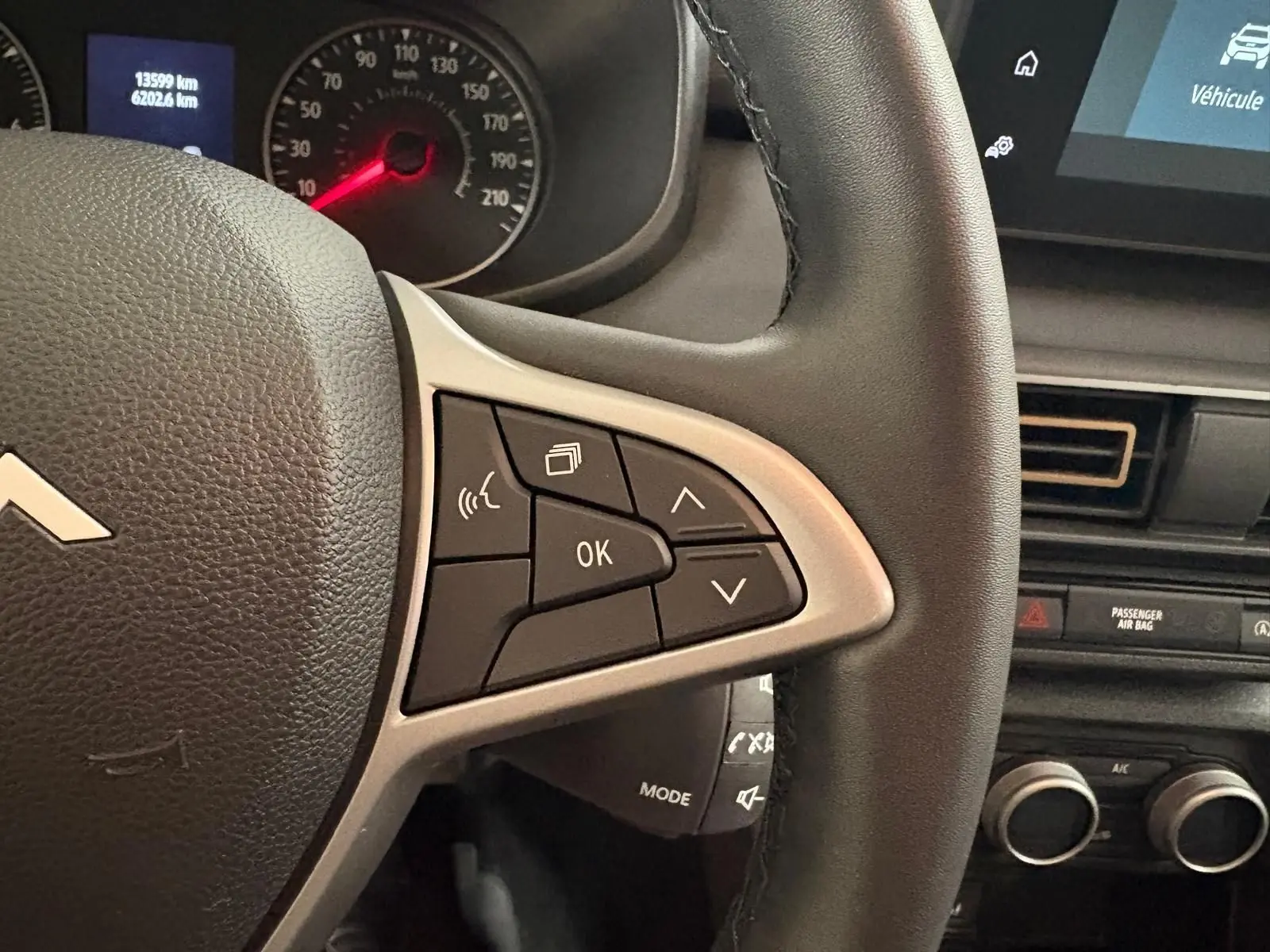 Gros plan sur le volant et le tableau de bord d'une Dacia Sandero Stepway 2023, détails des commandes au volant visibles.