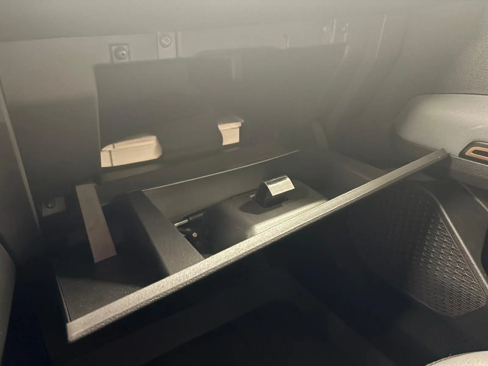 Intérieur du coffre à gants ouvert du Dacia Sandero Stepway 2023, montrant un rangement compartimenté en plastique noir.