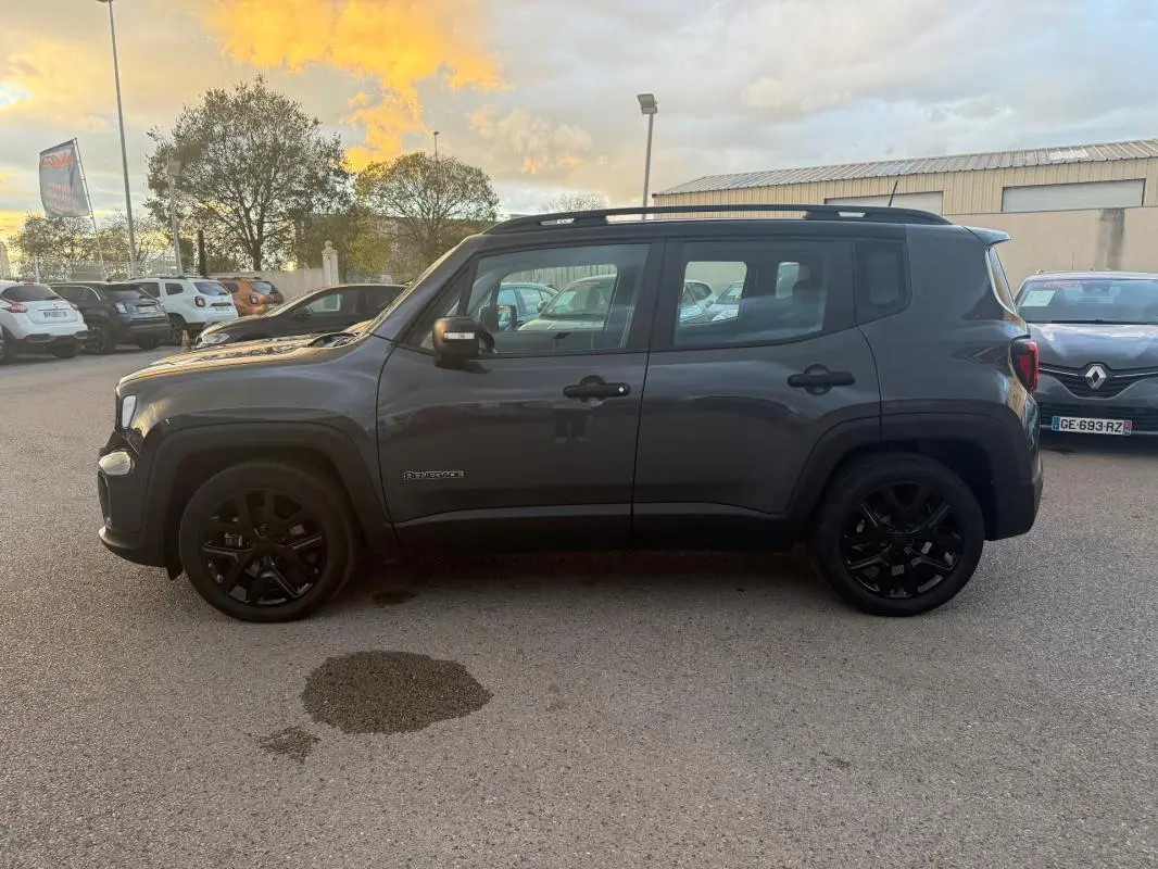 Vue de profil côté gauche d'un Jeep Renegade gris anthracite avec barres de toit et jantes alliage noires.
