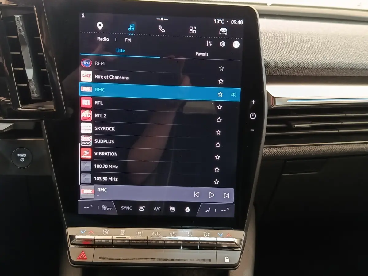 Vue rapprochée de l’écran tactile central de la Renault Mégane Techno EV60 220ch bleu, affichant les options radio et climatisation.