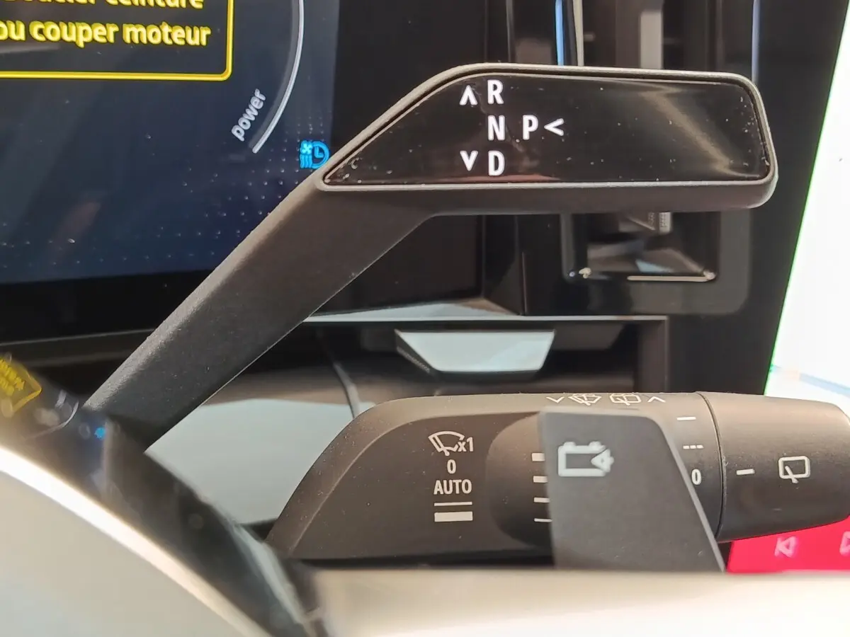 Gros plan sur la commande de boîte automatique et les commandes d’essuie-glace du tableau de bord d’une Renault Mégane EV60 bleu.