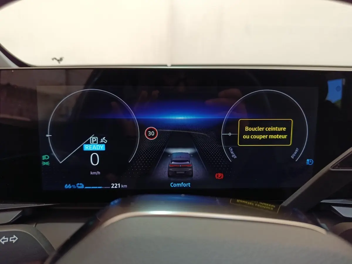 Tableau de bord numérique de Renault Mégane EV bleu, affichage vitesse, autonomie et alertes sécurité.