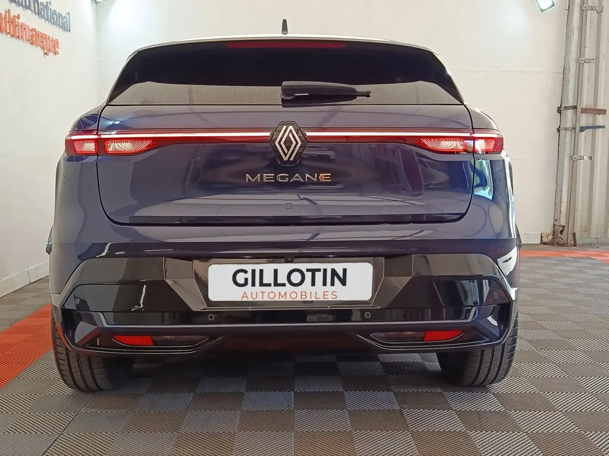 Vue arrière d'une Renault Mégane Techno EV60 bleu électrique avec feux arrière LED en bandeau lumineux.