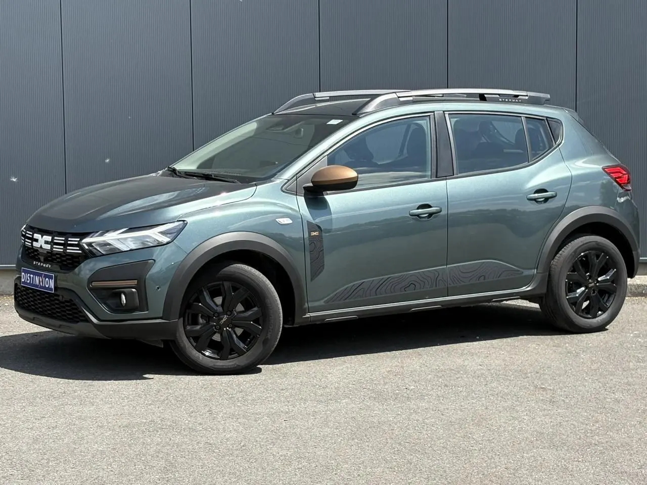 Vue de profil côté gauche d'une Dacia Sandero Stepway Vert Cèdre avec jantes noires et coques de rétroviseurs cuivrées.