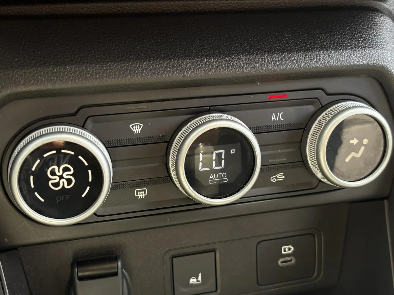 Gros plan sur la commande de climatisation automatique de la Dacia Sandero Stepway Vert Cèdre, avec affichage numérique et boutons rotatifs.