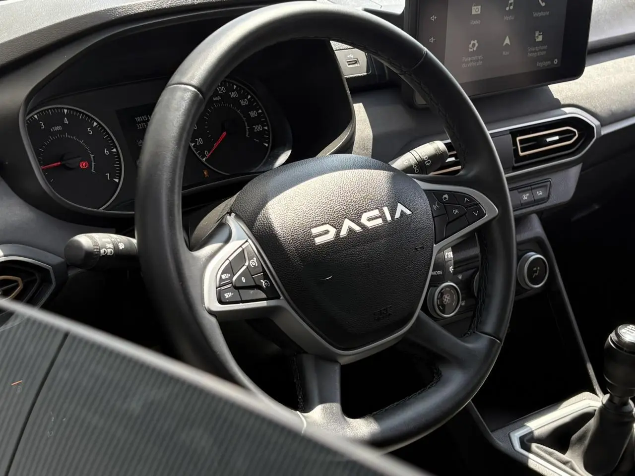 Vue rapprochée du volant noir Dacia et du tableau de bord avec écran tactile dans l’habitacle de la Sandero Stepway 2025.
