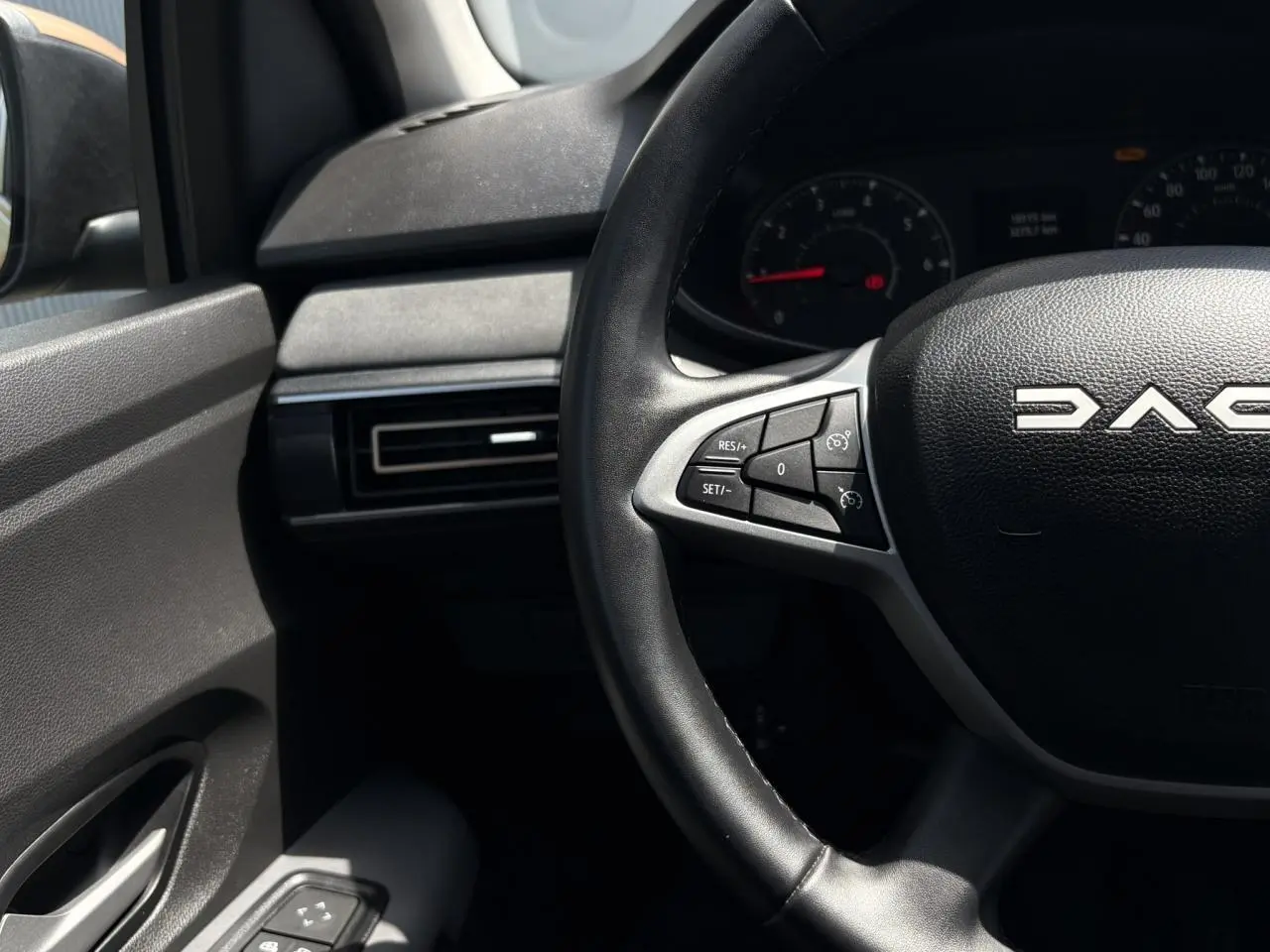Vue rapprochée du volant noir de la Dacia Sandero Stepway avec commandes intégrées et tableau de bord partiel.