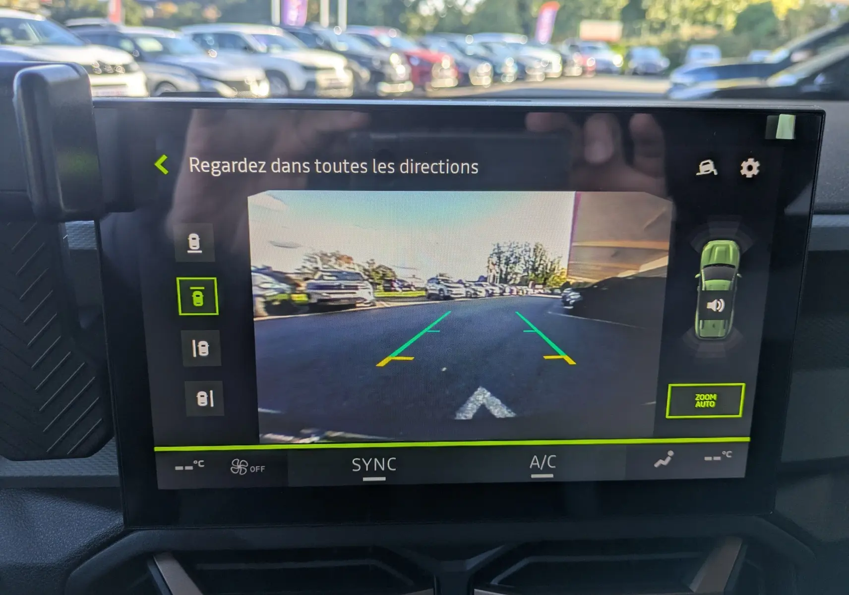 Écran multimédia tactile montrant la caméra de recul du Dacia Bigster Hybrid 155 Extreme bleu indigo en stationnement.
