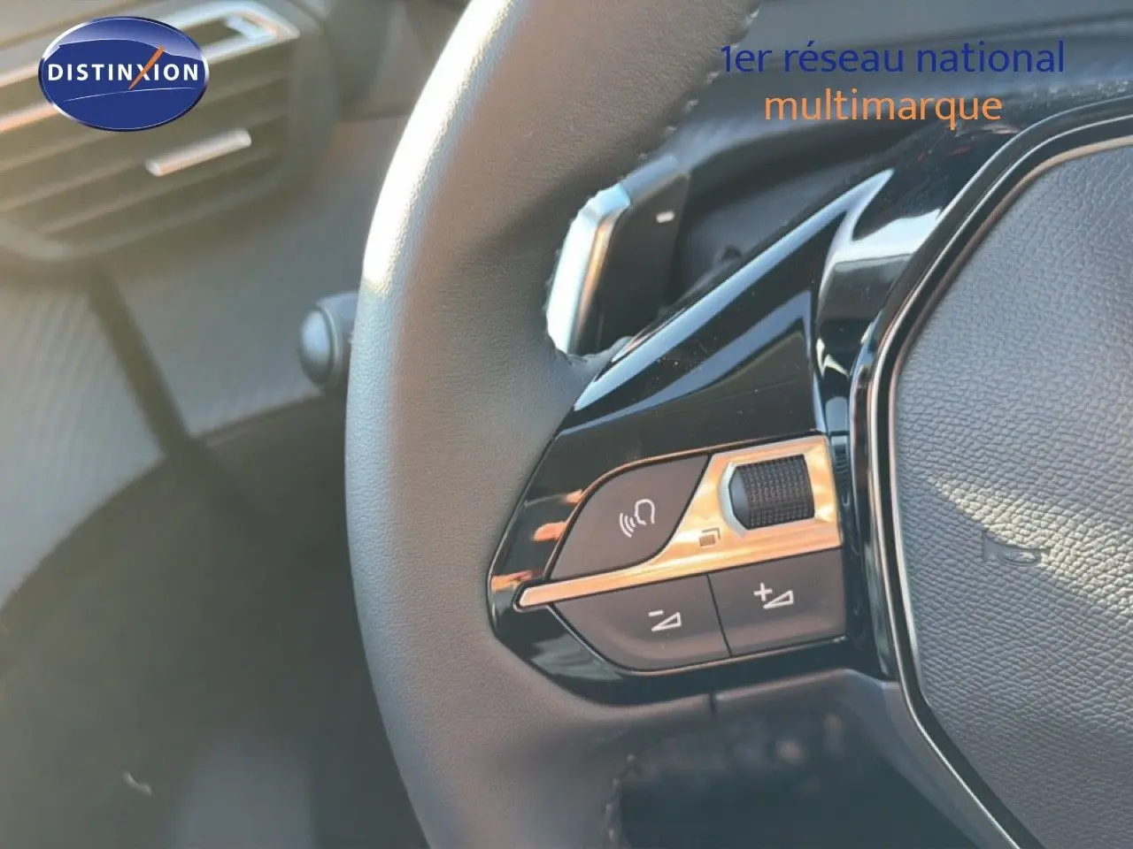 Détail des commandes sur le volant noir de la Peugeot 208 gris Artense Hybrid, mettant en valeur les boutons multifonctions.