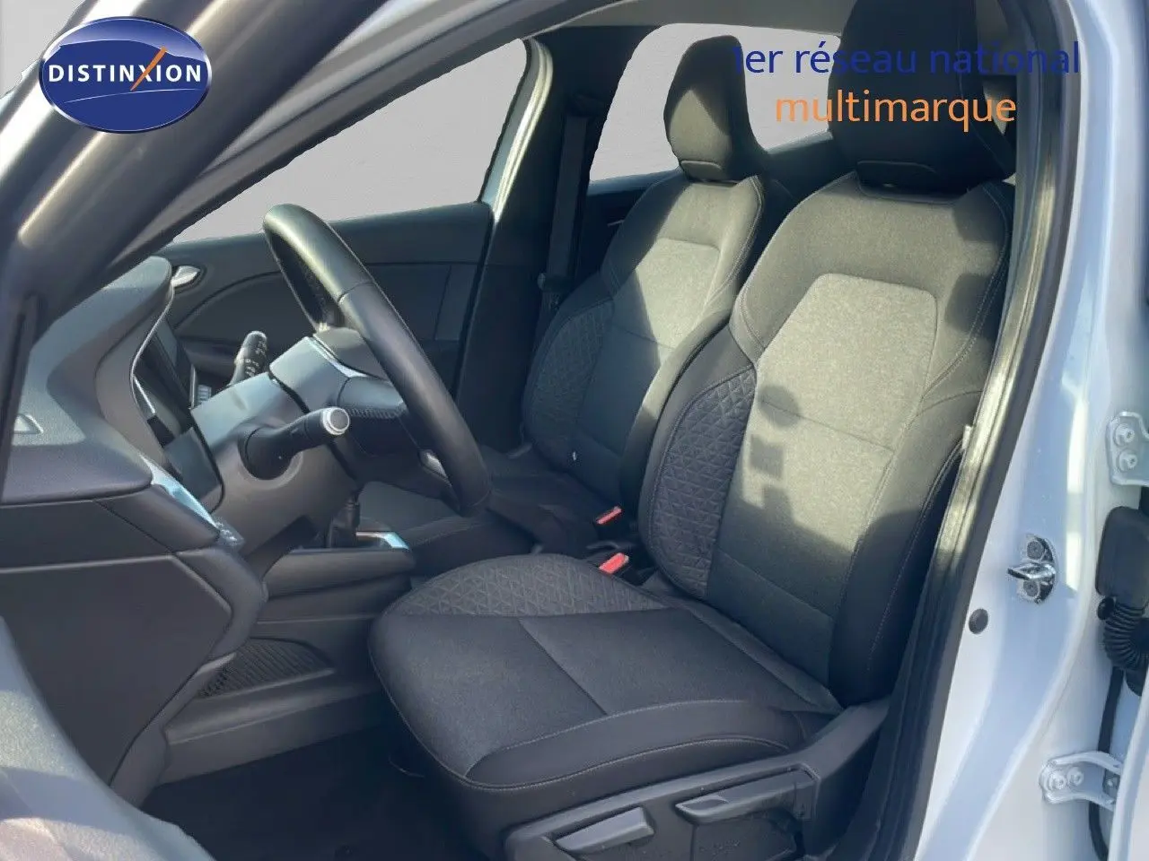 Intérieur de la Renault Clio blanc glacier vu côté conducteur, mettant en valeur les sièges tissu gris et le volant.