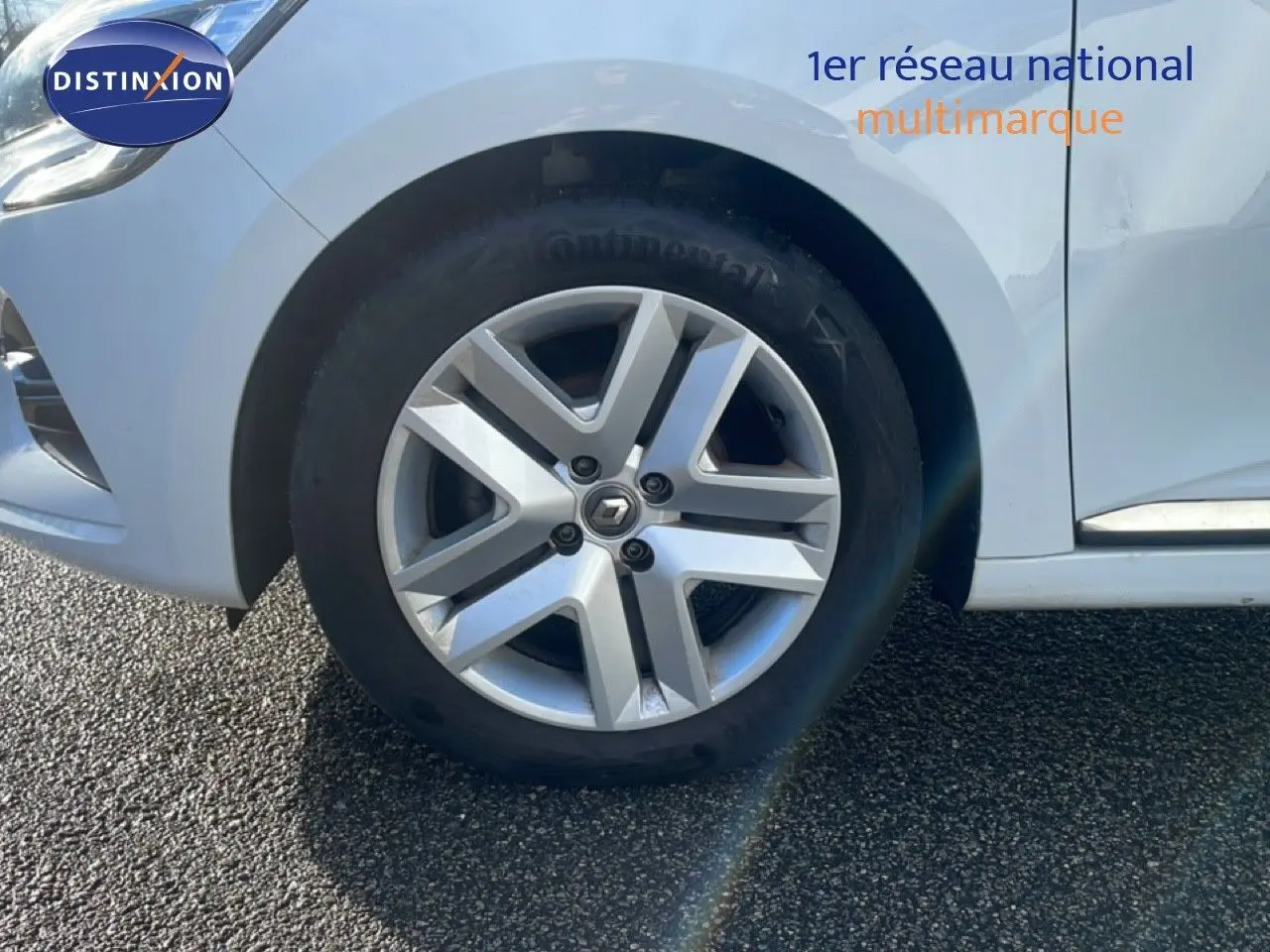 Gros plan sur la roue avant gauche de la Renault Clio blanche Glacier avec jante alliage et logo Renault central.