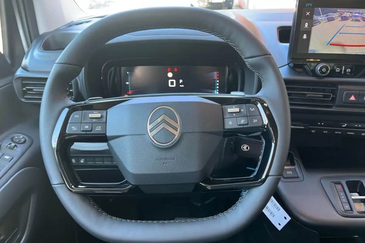 Vue rapprochée du volant cuir multifonctions noir et tableau de bord numérique du Citroën Berlingo 2025.