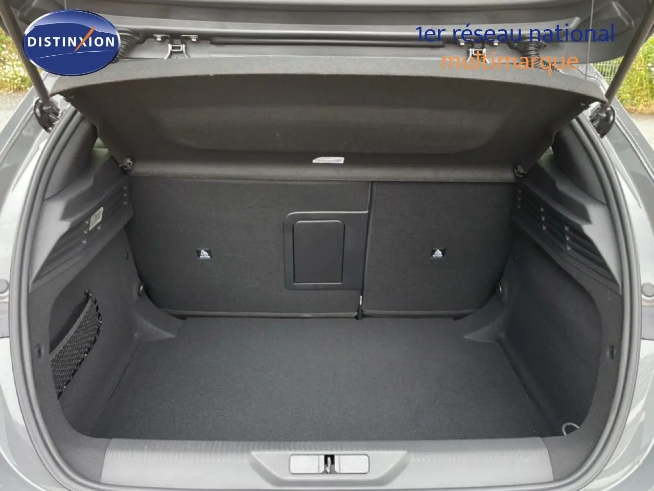 Coffre ouvert vu de l'arrière d'une Peugeot 308 gris selenium metal, montrant un espace de chargement propre et spacieux.