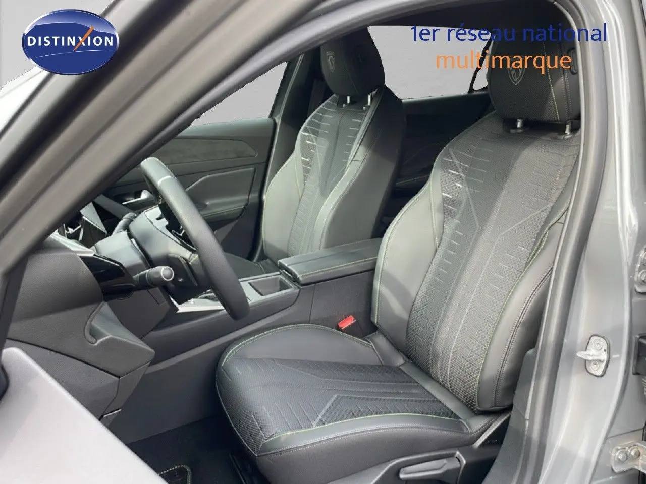 Vue intérieure côté conducteur de la Peugeot 308 gris selenium, sièges en tissu noir avec surpiqûres vertes et volant multifonction.