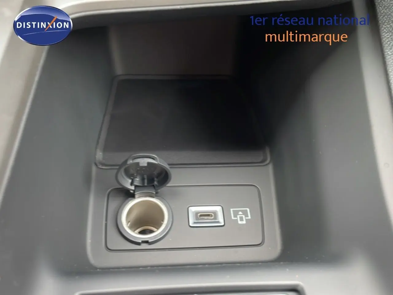 Prise allume-cigare et port USB-C dans la console centrale d'une Peugeot 308 gris selenium metal, version hybride 2026.