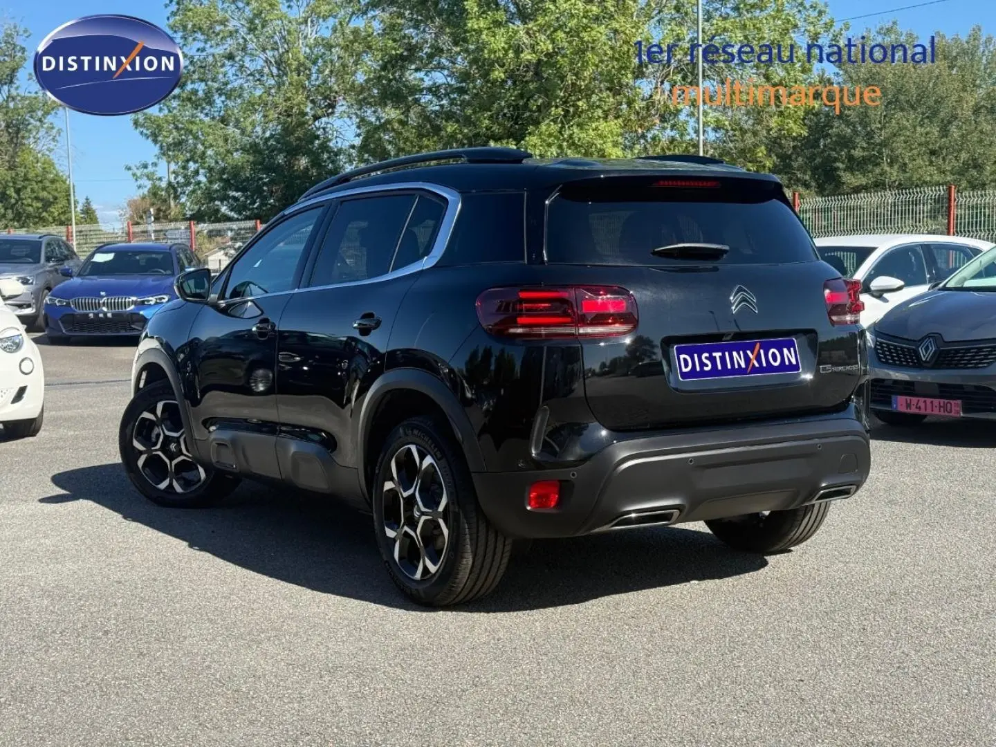 Vue 3/4 arrière droite d'un Citroën C5 Aircross noir Perla Nera avec jantes alu et barres de toit visibles.