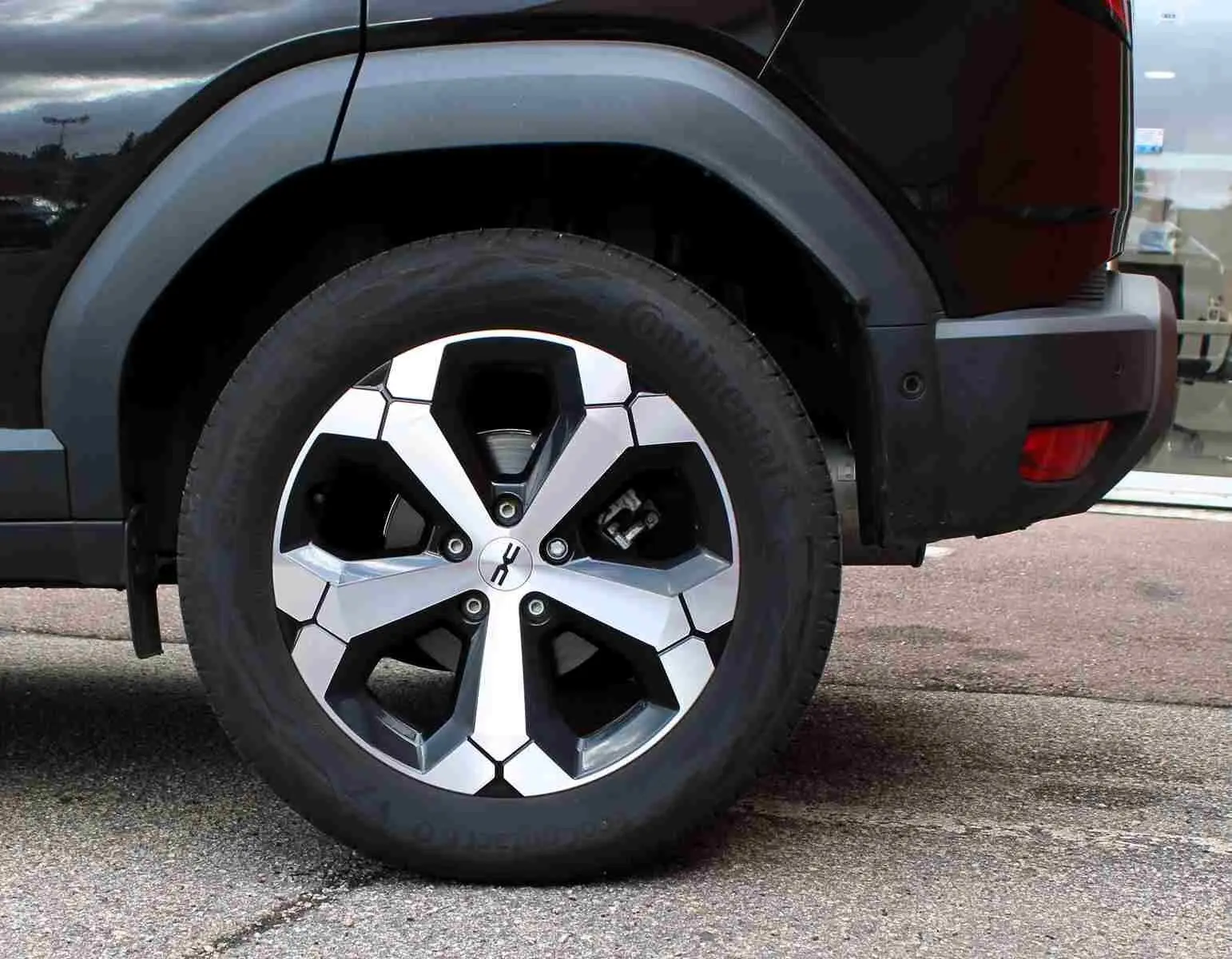 Gros plan sur la roue arrière droite du Dacia Duster noir 2025 avec jante alliage diamantée Tagasan.