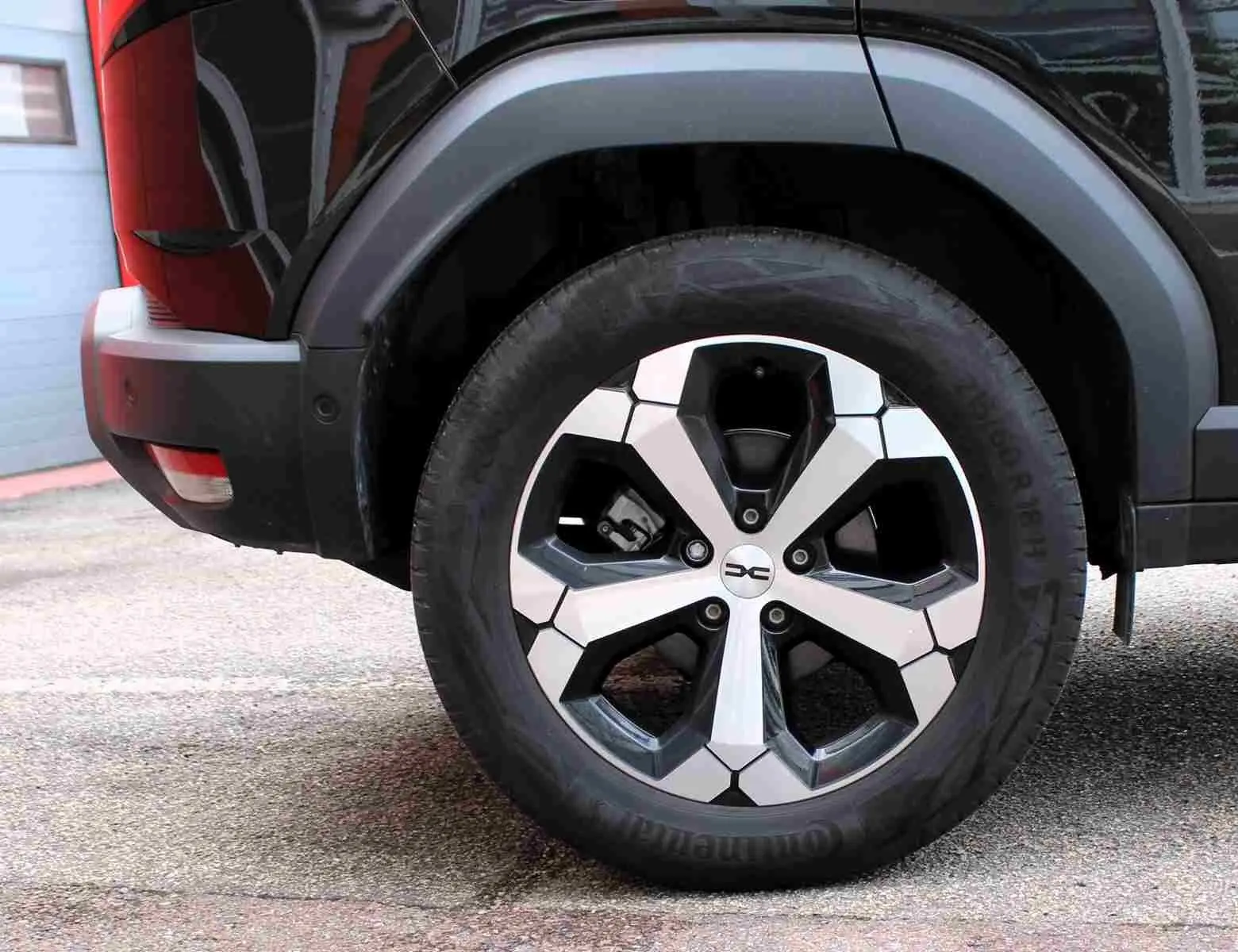 Gros plan sur la roue arrière droite du Dacia Duster 2025 noire avec jante alliage 18 pouces diamantée Tagasan.