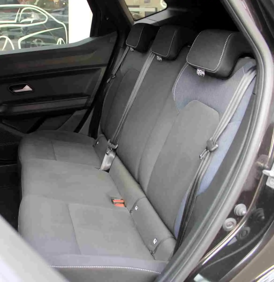 Vue côté droit de la banquette arrière du Dacia Duster 2025, sellerie Denim bleu et ceintures de sécurité grises.