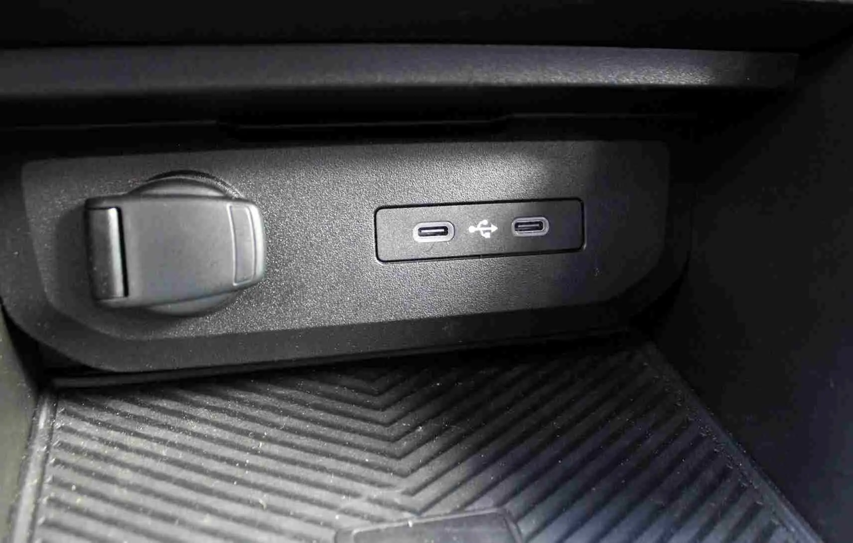 Gros plan sur la console centrale du Dacia Duster III noire, montrant deux prises USB type C et une prise 12V.
