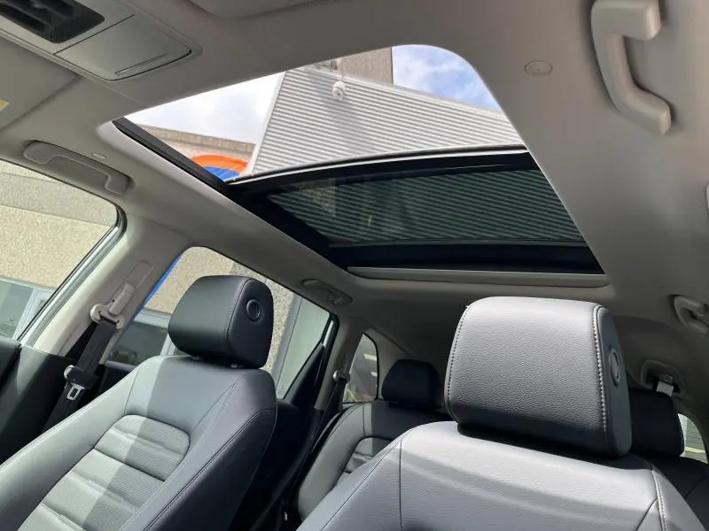 Vue intérieure du toit panoramique ouvert et sièges cuir noir du Honda CR-V 2024, lumière naturelle traversante.