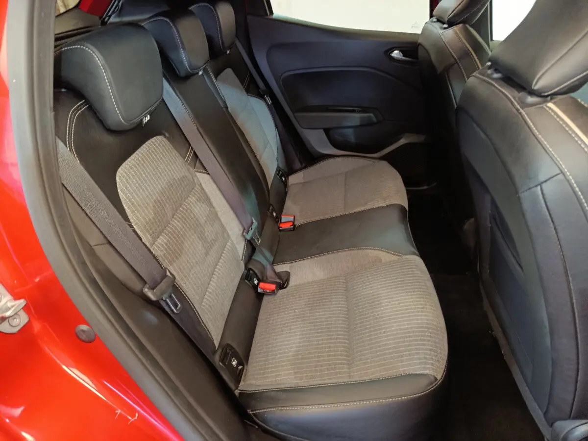 Vue intérieure sur la banquette arrière côté gauche d'une Renault Clio Techno TCe 90 rouge avec sièges bicolores tissu et cuir.