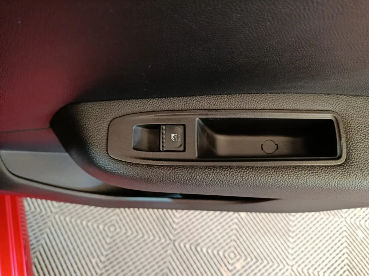 Gros plan sur la commande de lève-vitre côté conducteur de la Renault Clio Techno TCe 90 rouge 2024.